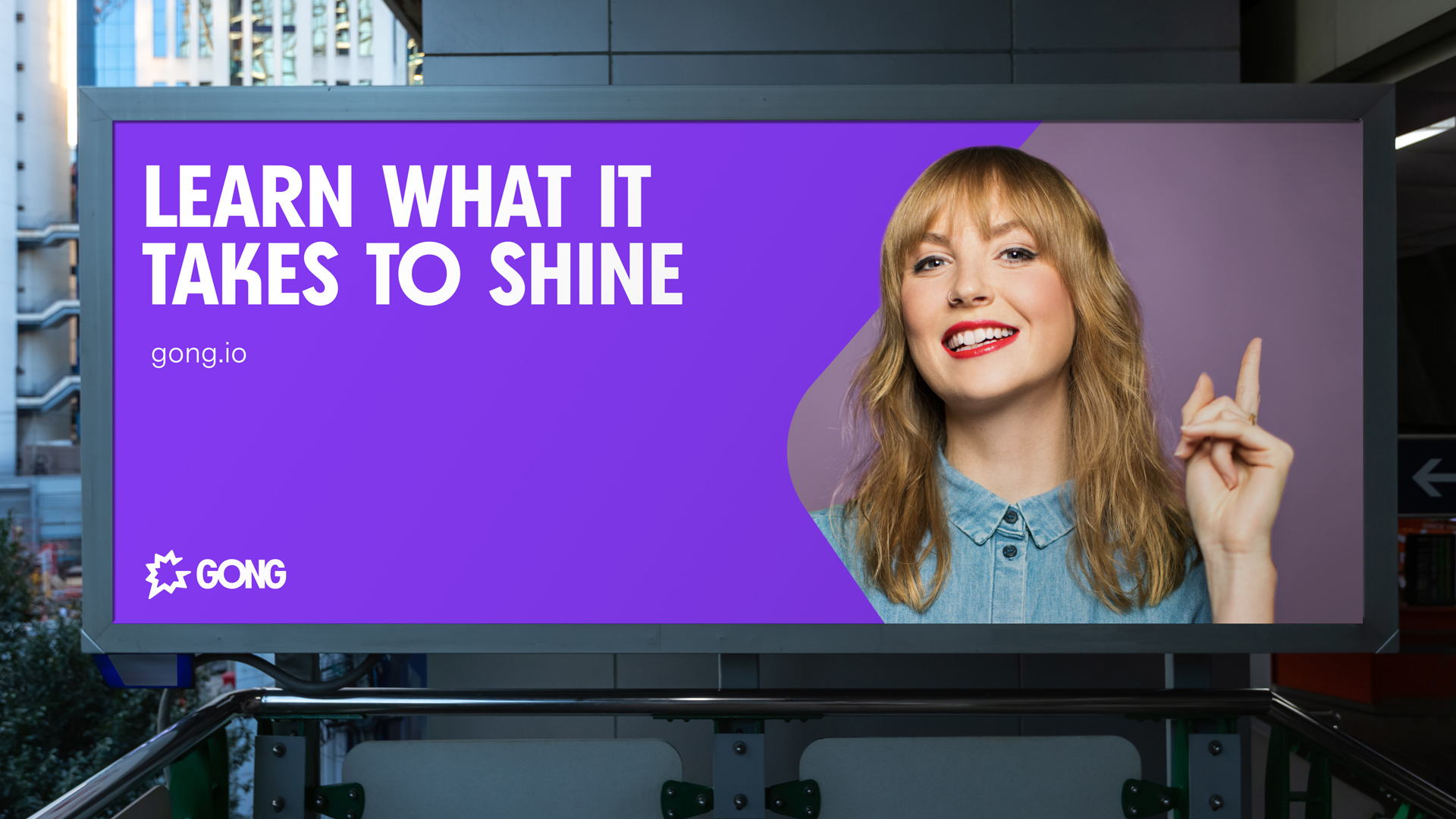 An out of home large poster that features a woman smiling and the title “Learn what it takes to shine”.